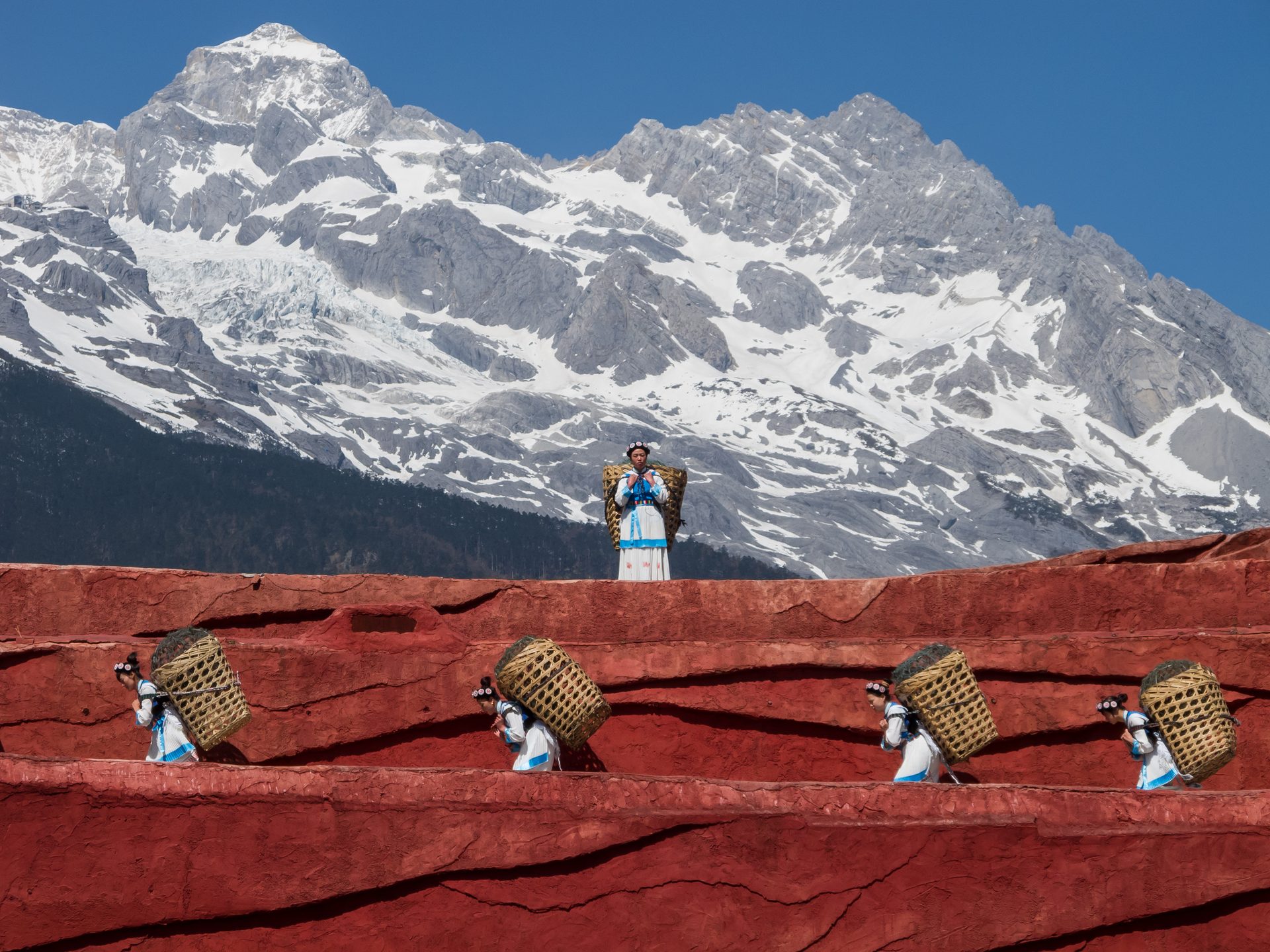 Naxi women in traditional dress carrying woven baskets in Lijiang